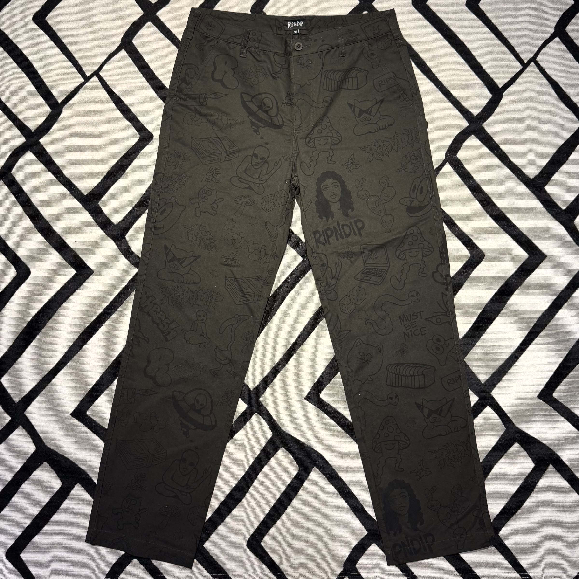 frente da calça RipNDip verde-oliva com estampa doodle